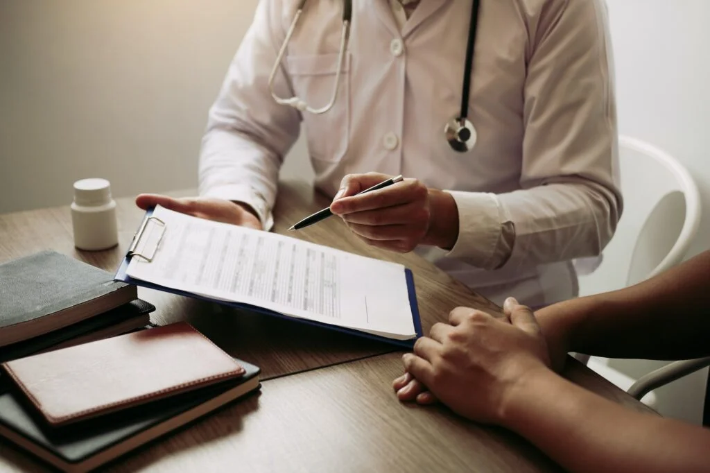 Doctor is writing the appointment letter to the patient at the clinic.